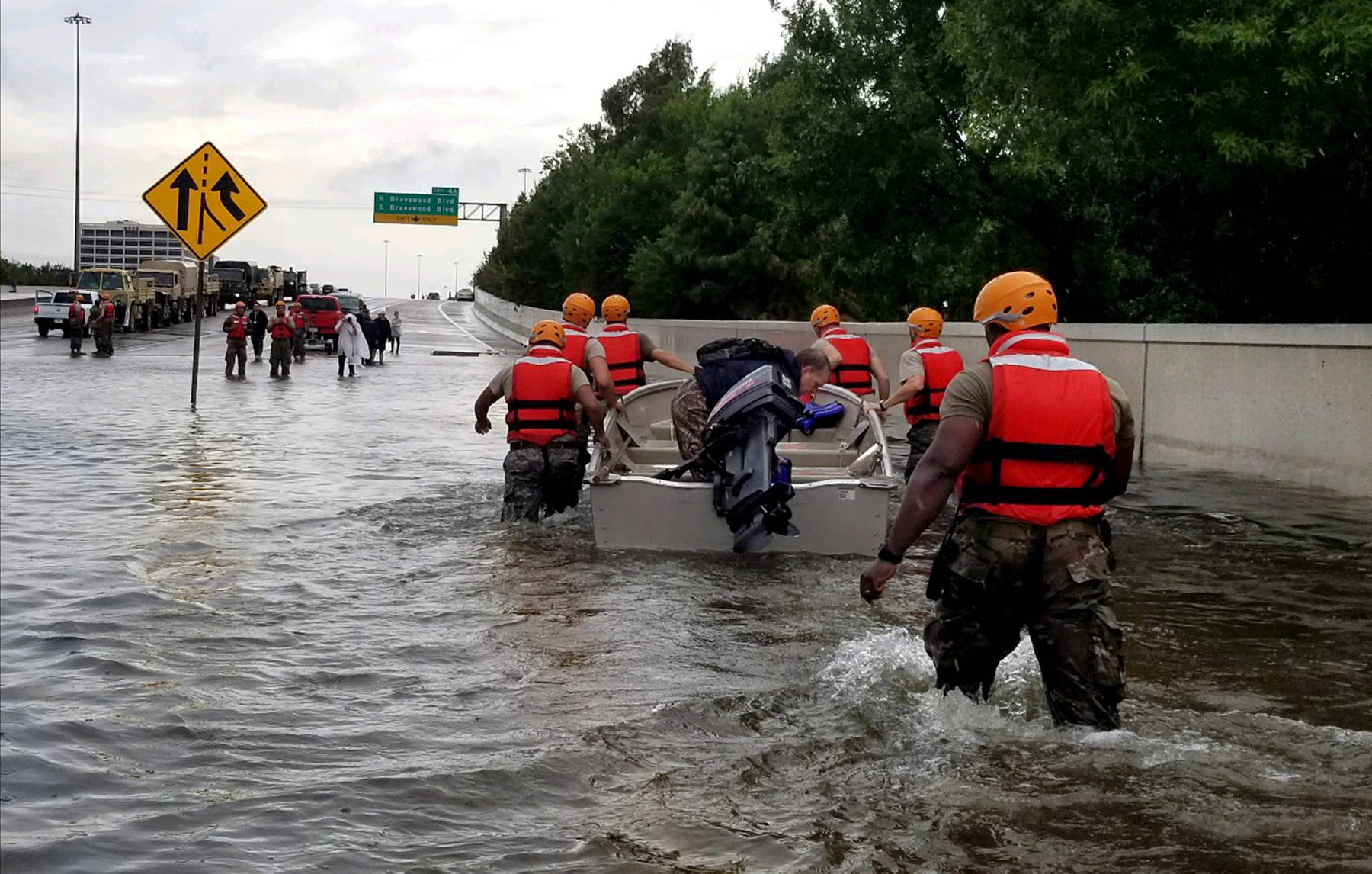 Texas Army National Guard members in life vests push a small boat down a flooded Houston freeway during Hurricane Harvey.